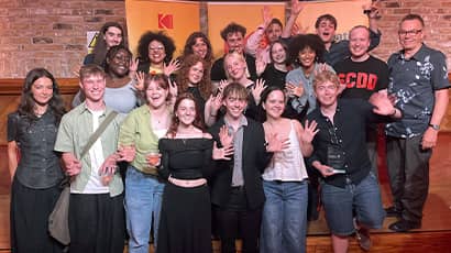 A group of celebrating students smile at the camera.
