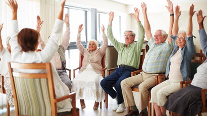 Daily stretching exercise routine for a group of cheerful elderly people at an old age home.