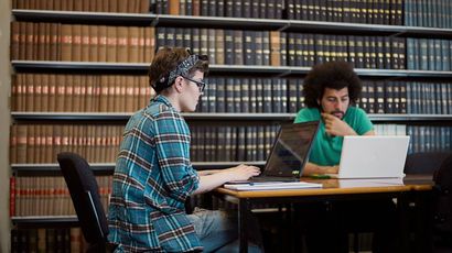 Two people sitting at a table reading.