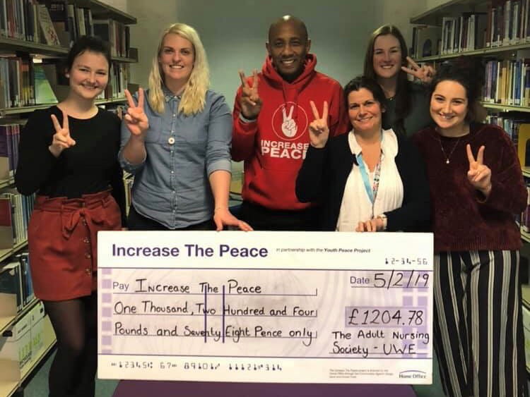 Adult Nursing Society members holding oversized cheque for charity.