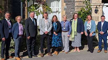 A group of people smiling at the camera while standing outside an historic building