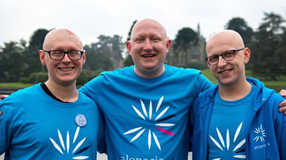 Three men standing together to camera in blue Alopecia UK t-shirts.