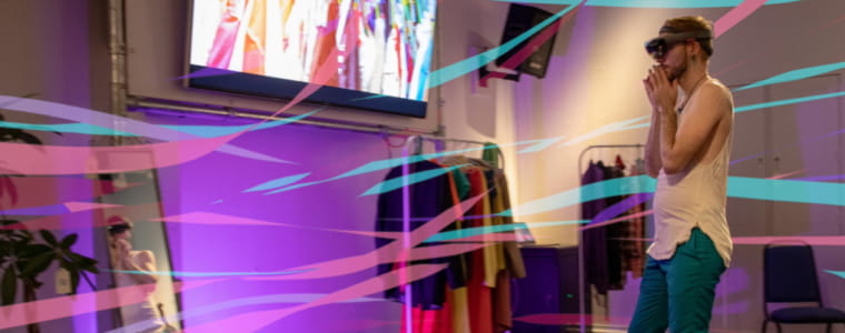 Man wearing VR headset near screen showing fashion items.