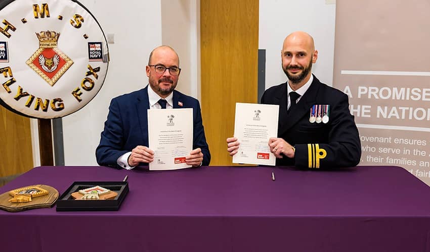 Professor Marc Griffiths (from UWE Bristol) and Lieutenant Commander Dominic Simonis-Law seated at a formal signing ceremony