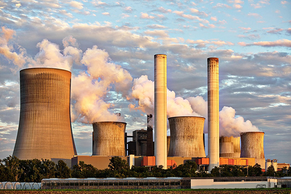 An image of a factory with large smoke stacks.