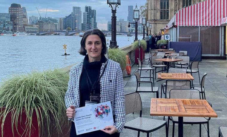 Professor Nikki Cotterill holding copy of Voice of Change report with the Thames, London in background.