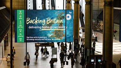 A blue and green digital advertising screen at a tube station in London