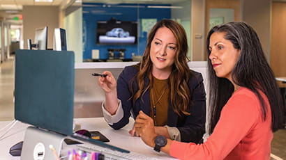 Two women in an office discussing and looking at a laptop