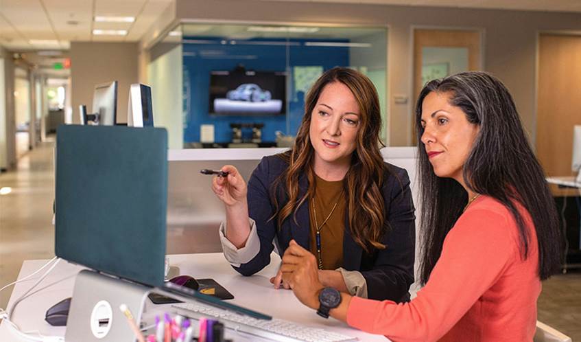 Two women in an office discussing and looking at a laptop