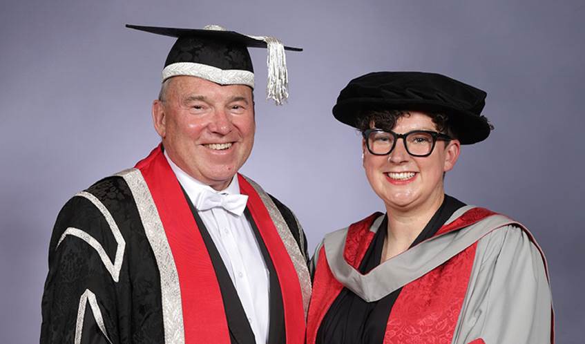 Professor Sir Steve West (left) with Clare Reddington (right), wearing black caps and red gowns at a graduation ceremony