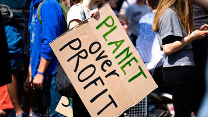 Close up of a group with a cardboard banner central reading 'Planet over Profit'.