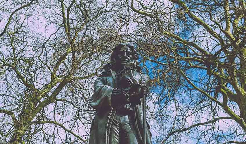 Image of the Edward Colston statue, with trees in the background, in Bristol city centre before it was removed in 2020