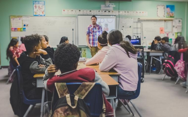 Group of students in a classroom listening to their teacher.