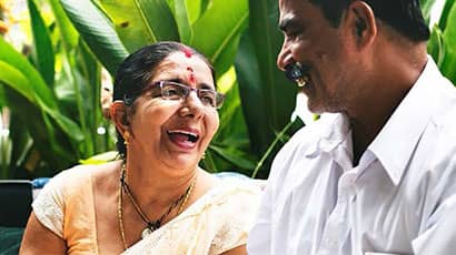 Lady dressed in sari smiling up at man.