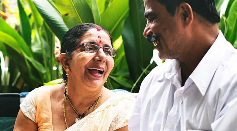 Lady dressed in sari smiling up at man.