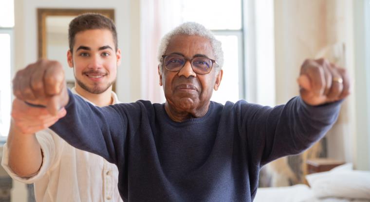 Healthcare worker and older person exercising together.