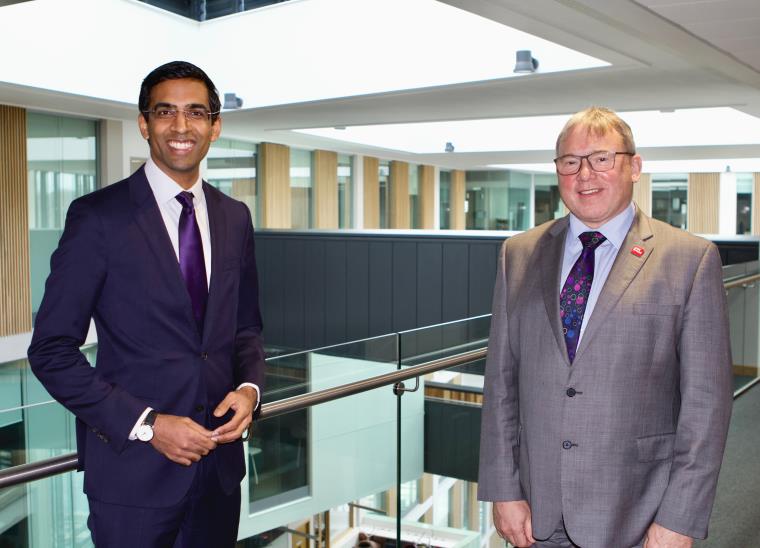 Rishi Sunak and Professor Steve West smiling to camera in front of bookshelves.