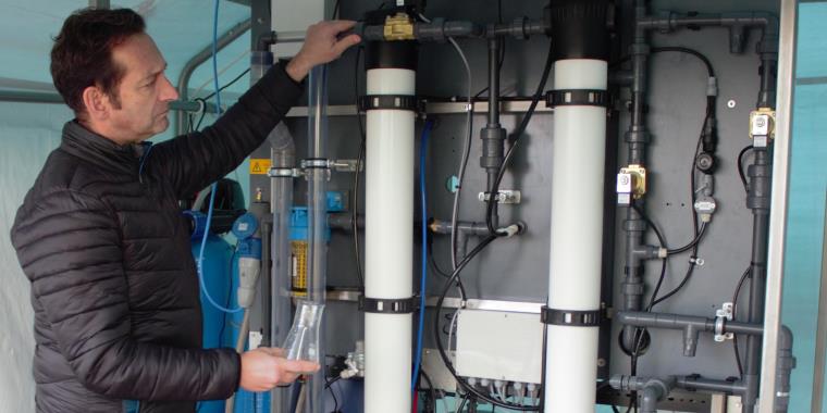 Man examining two large wall-mounted metallic cylinders.