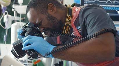 Man focusing as he takes a photograph using an SLR camera in a clinical setting
