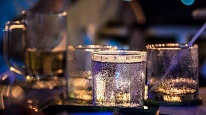 Picture of two glasses with drinks in a bar setting.