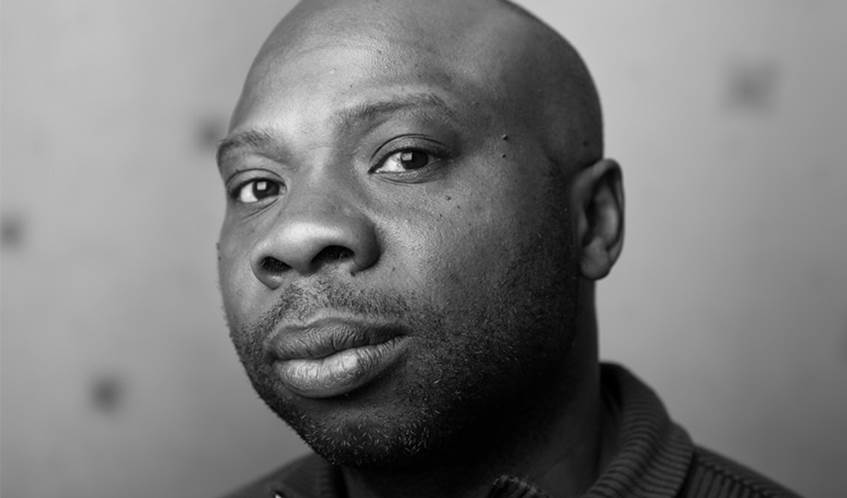 A black and white headshot of a man looking directly to camera