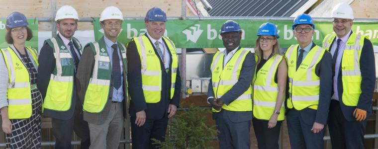 Group of 8 people in hardhats and high-vis clothing for the topping out of the Engineering Building at Frenchay Campus.