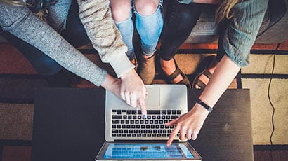 Three people working on a laptop computer