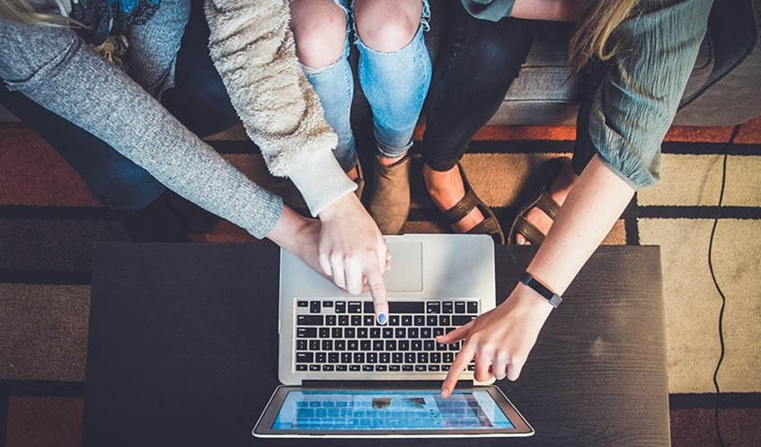Three people working on a laptop computer