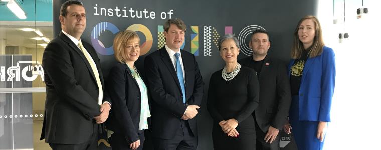 Group smiling together in front of Institute of Coding banner.