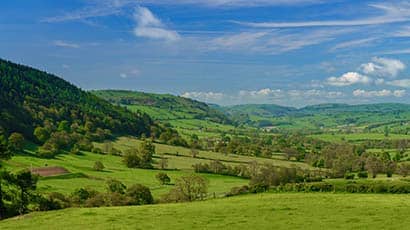 Image of grassland hills in the UK with blue sky and scattered clouds