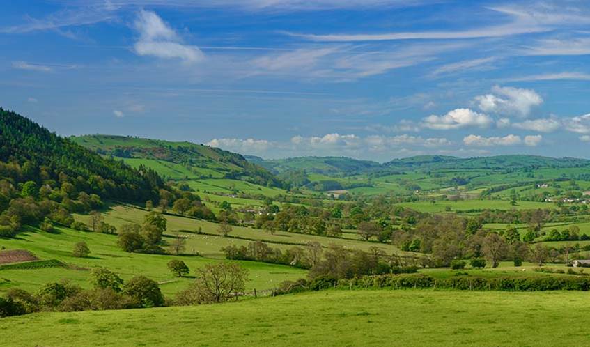 Image of grassland hills in the UK with blue sky and scattered clouds