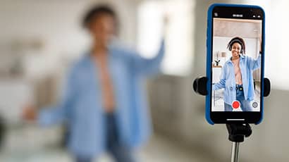 Image showing a social media influencer filming themselves with a mobile phone attached to a selfie stick