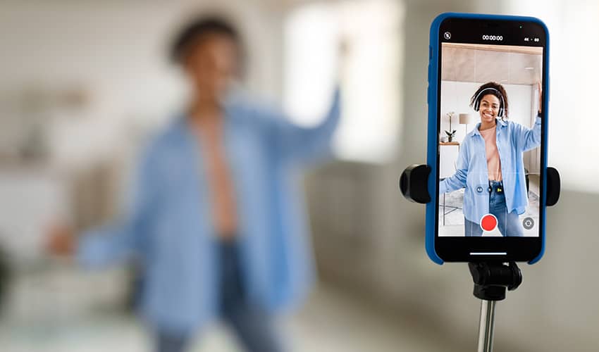 Image showing a social media influencer filming themselves with a mobile phone attached to a selfie stick