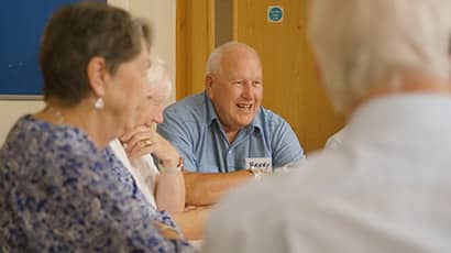 Photo of a dementia support celebration event, showing four people sat around a table