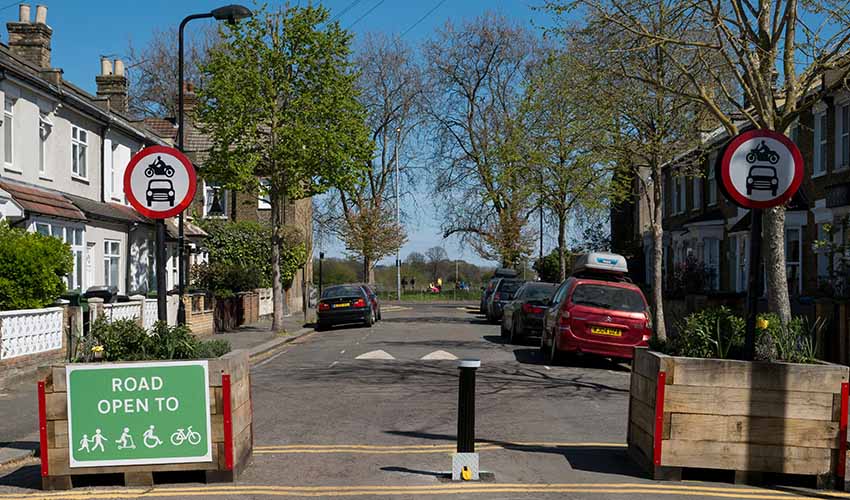 Street of terraced houses with a modal filter banning cars from entering but allowing cyclists and pedestrians