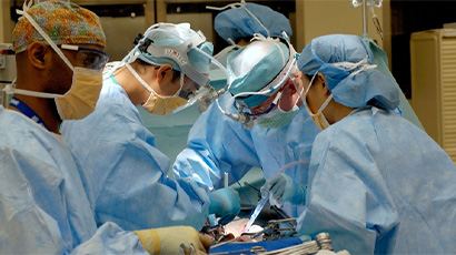 A team of surgeons performing open surgery in theatre.
