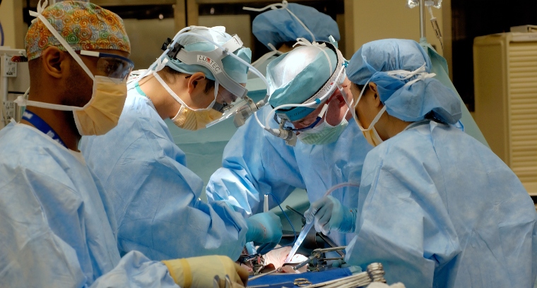 A team of surgeons performing open surgery in theatre.