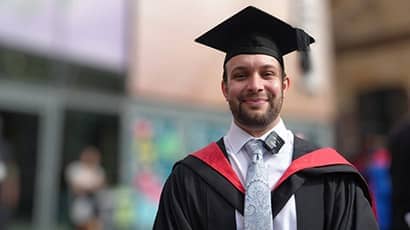 Michael Rose in his cap and gown on his graduation day, stood outside Bristol Beacon