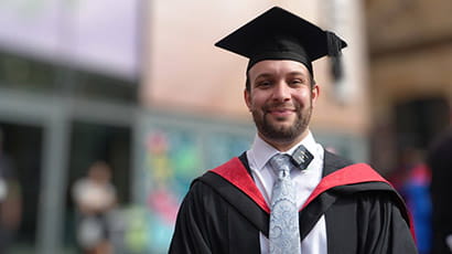 Michael Rose in his cap and gown on his graduation day, stood outside Bristol Beacon