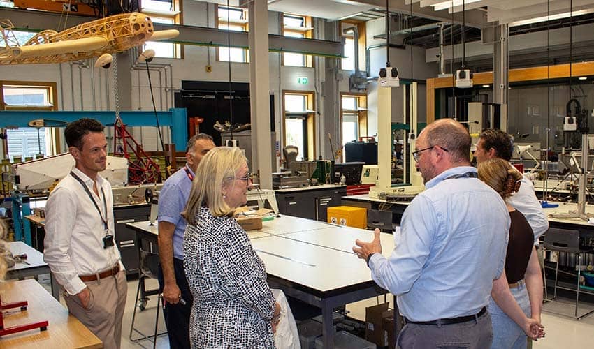 Six people standing in an engineering teaching room having a discussion