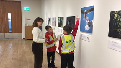 Schoolchildren showing their teacher the photography hung in the gallery at their school.