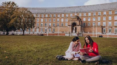 Two UWE Bristol students seated on the grass at College Green.