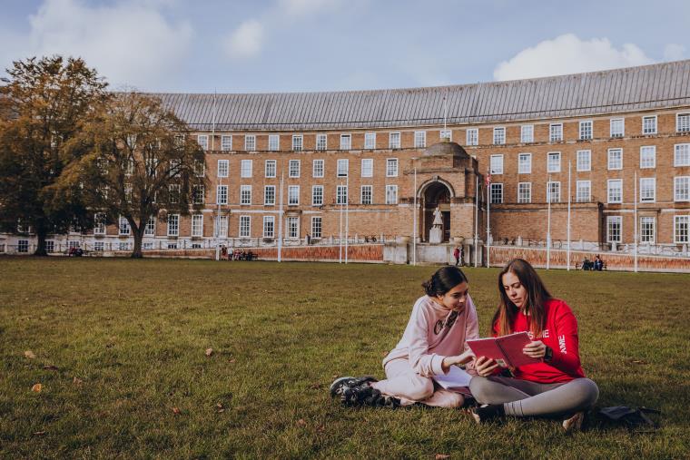 Two UWE Bristol students seated on the grass at College Green.