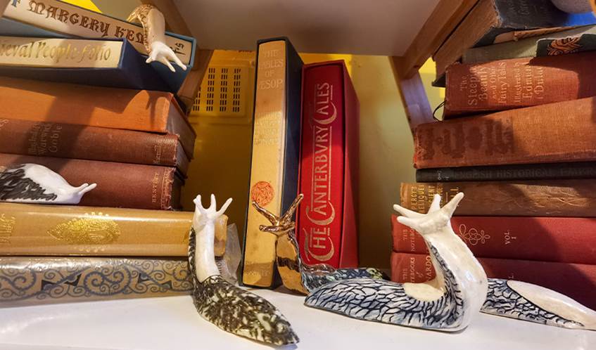 Ceramic slugs crawl around some books stacked on a shelf.