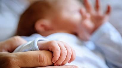 A newborn baby holding the hand of a parent