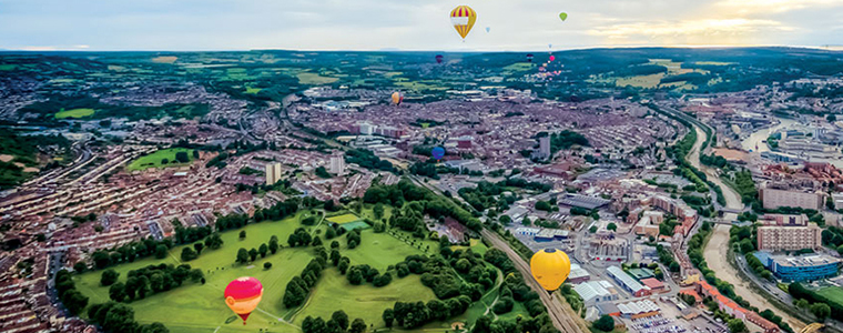 An image of Bristol city from above with hot air balloons flying around