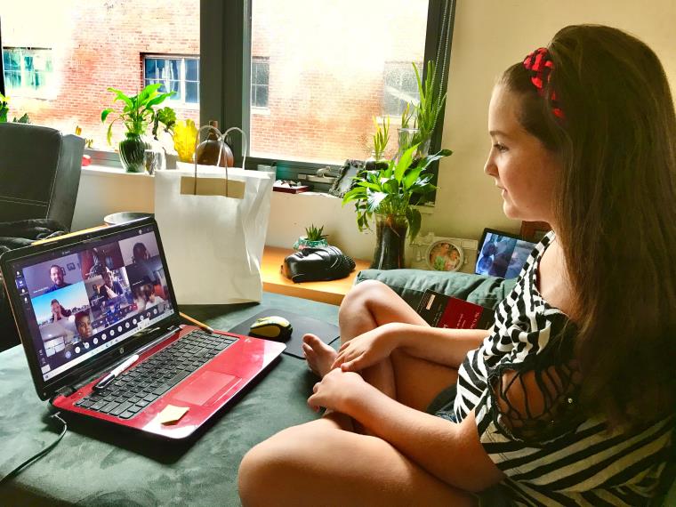 A young girl attending an online class via her laptop