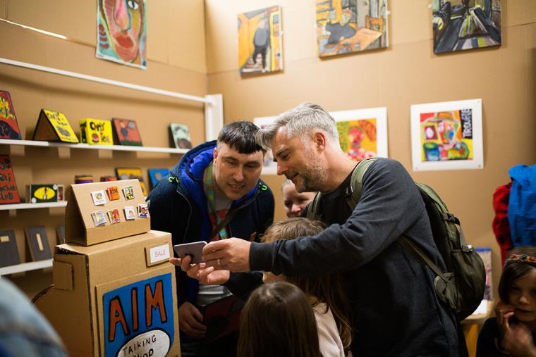 Two men and children looking at artworks