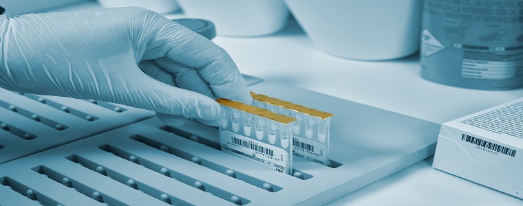 A human hand wearing a medical glove taking out a sample in a laboratory.