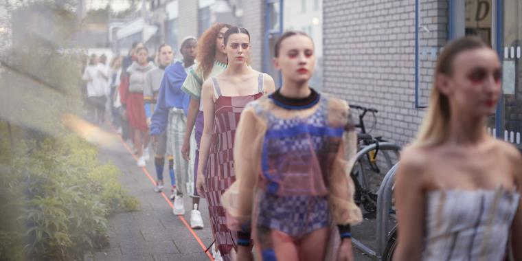 Models walking on catwalk outside of a building